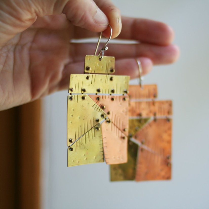 Ručně vyrobené výrazné náušnice z mědu a mosazi - sešité pohyblivými spojami z různých tvarů do velkých obdélníků - foceno visící v ruce